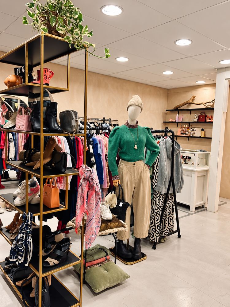 Winkelinterieur met een rek schoenen, tassen en een paspop