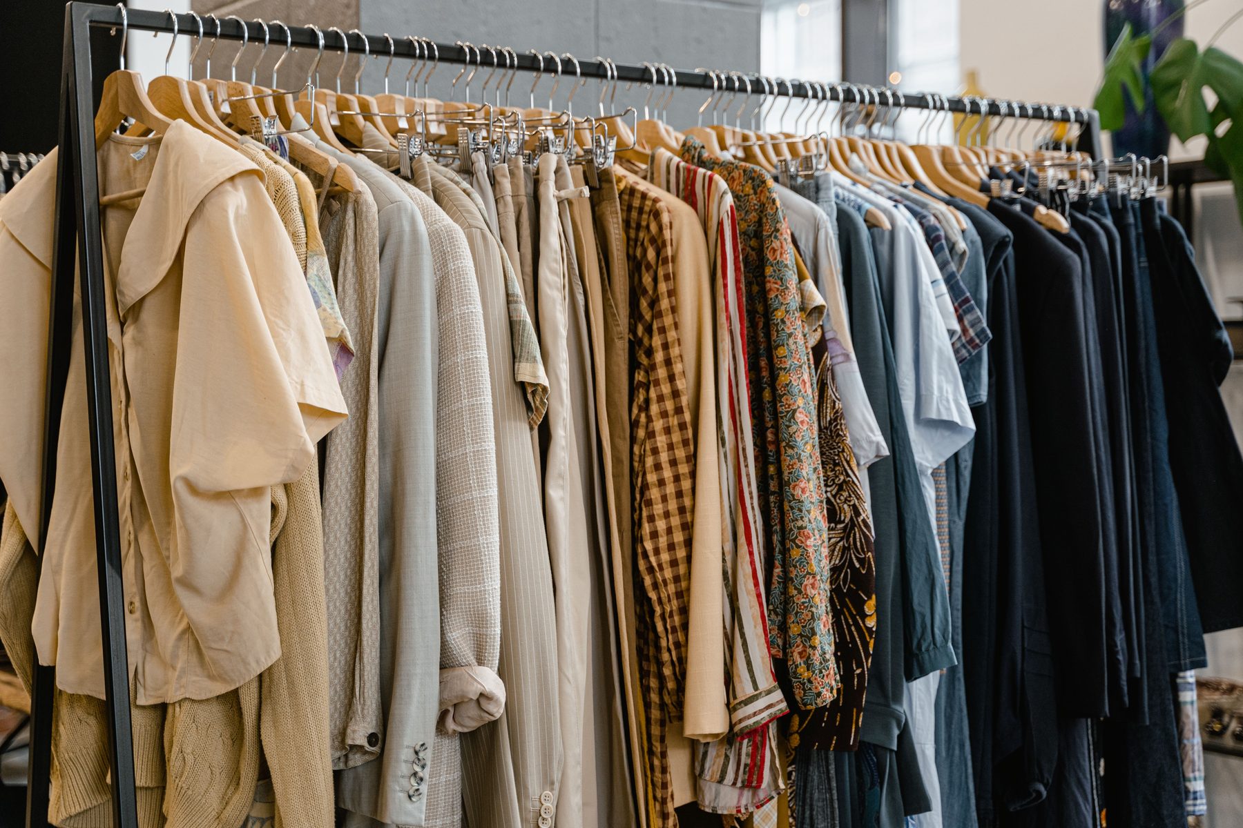 Kledingrek met truien, jassen en blouses in aardetinten