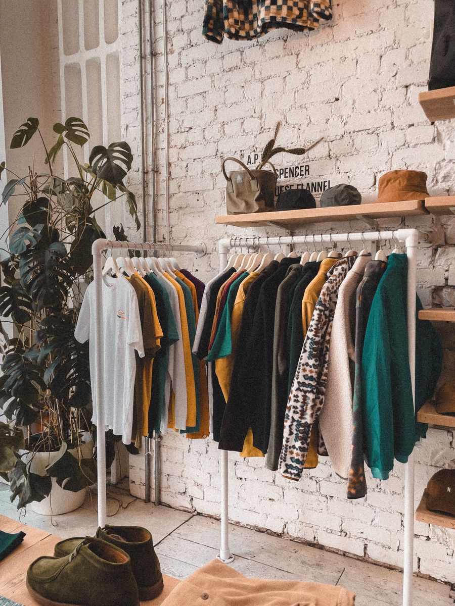 Winkelinterieur met een kledingrek, een grote plant en een witte bakstenen muur